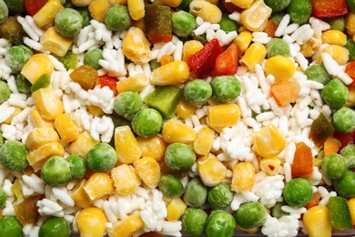 Photo of Frozen vegetable mix with rice as background, closeup