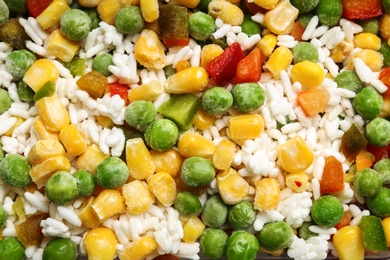 Frozen vegetable mix with rice as background, closeup