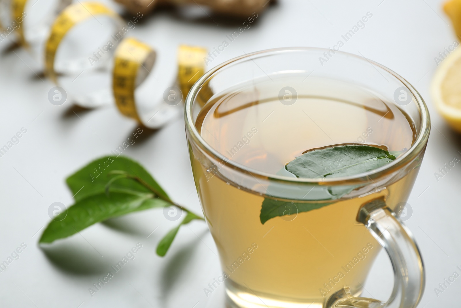 Photo of Herbal diet tea and measuring tape on light table, closeup