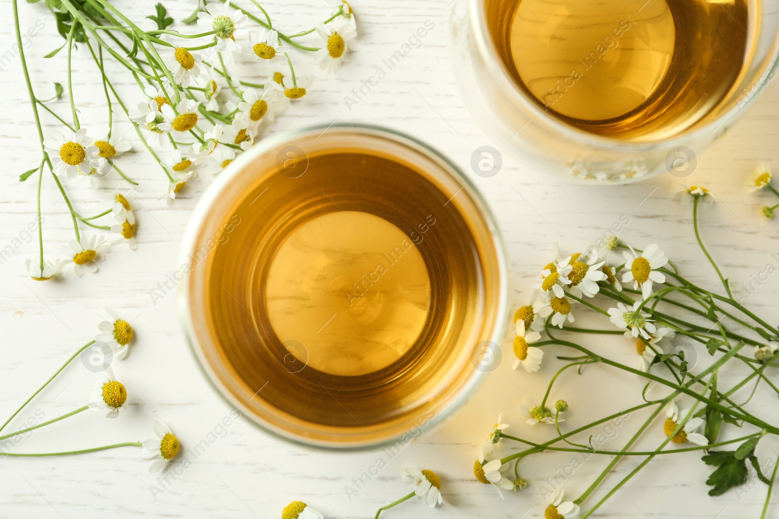 Photo of Flat lay composition with tea and chamomile flowers on white wooden table