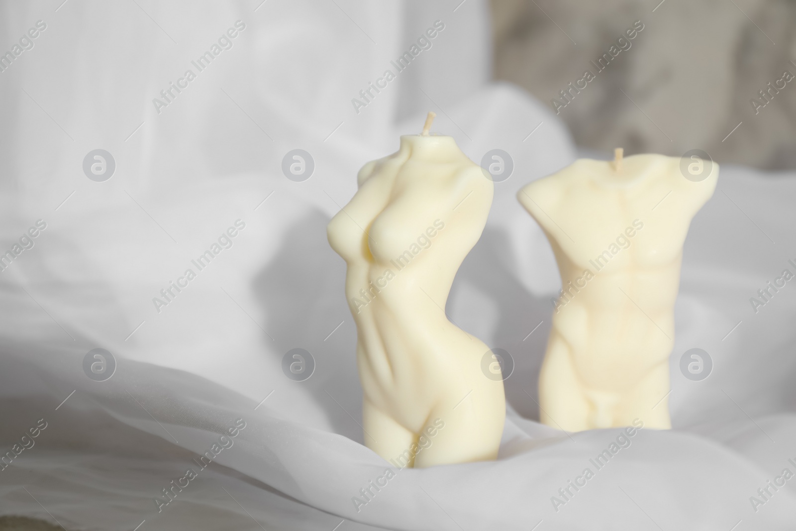 Photo of Beautiful male and female body shaped candles on fabric