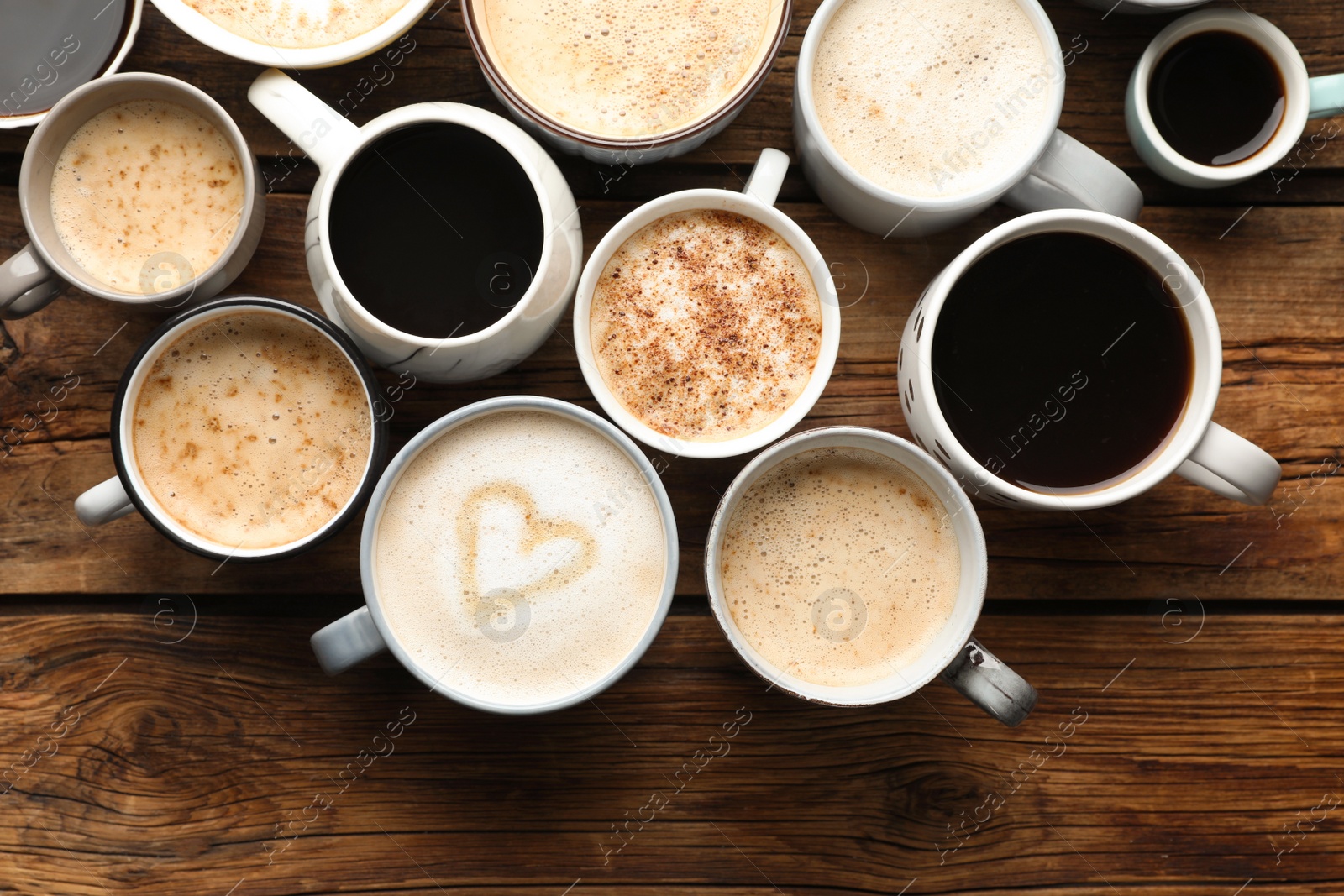 Photo of Many cups of different coffees on wooden table, flat lay