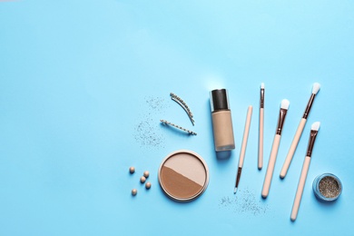 Flat lay composition with makeup brushes on light blue background. Space for text