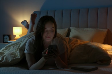 Woman using smartphone in bed at night. Internet addiction