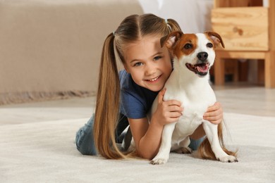 Photo of Cute girl with her dog on floor at home. Adorable pet