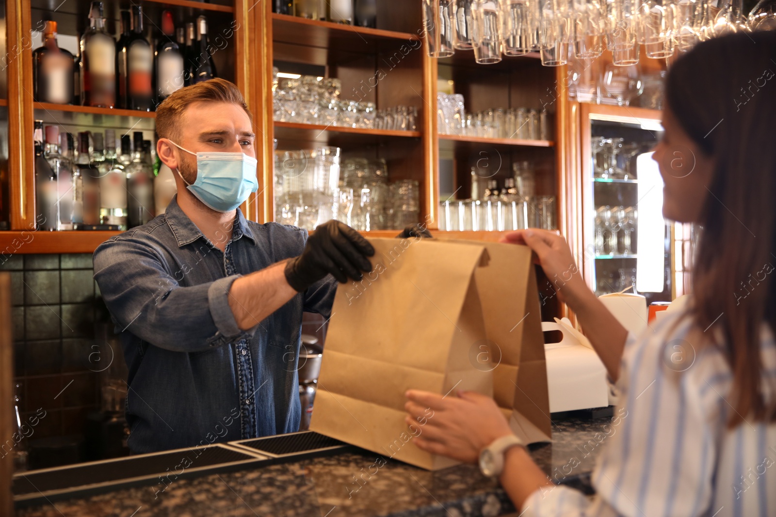 Photo of Waiter giving packed takeout order to customer in restaurant. Food service during coronavirus quarantine