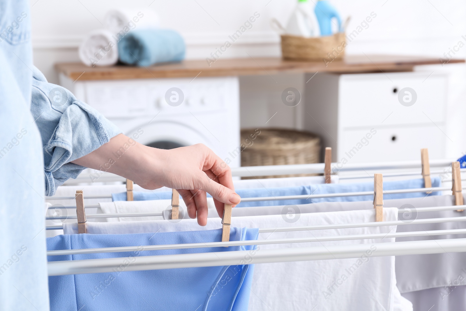 Photo of Woman hanging clean laundry on drying rack in bathroom, closeup