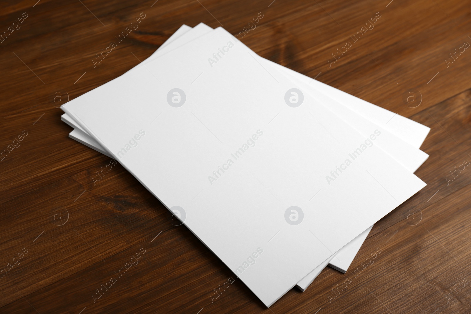 Photo of Stack of blank paper sheets on wooden table. Brochure design