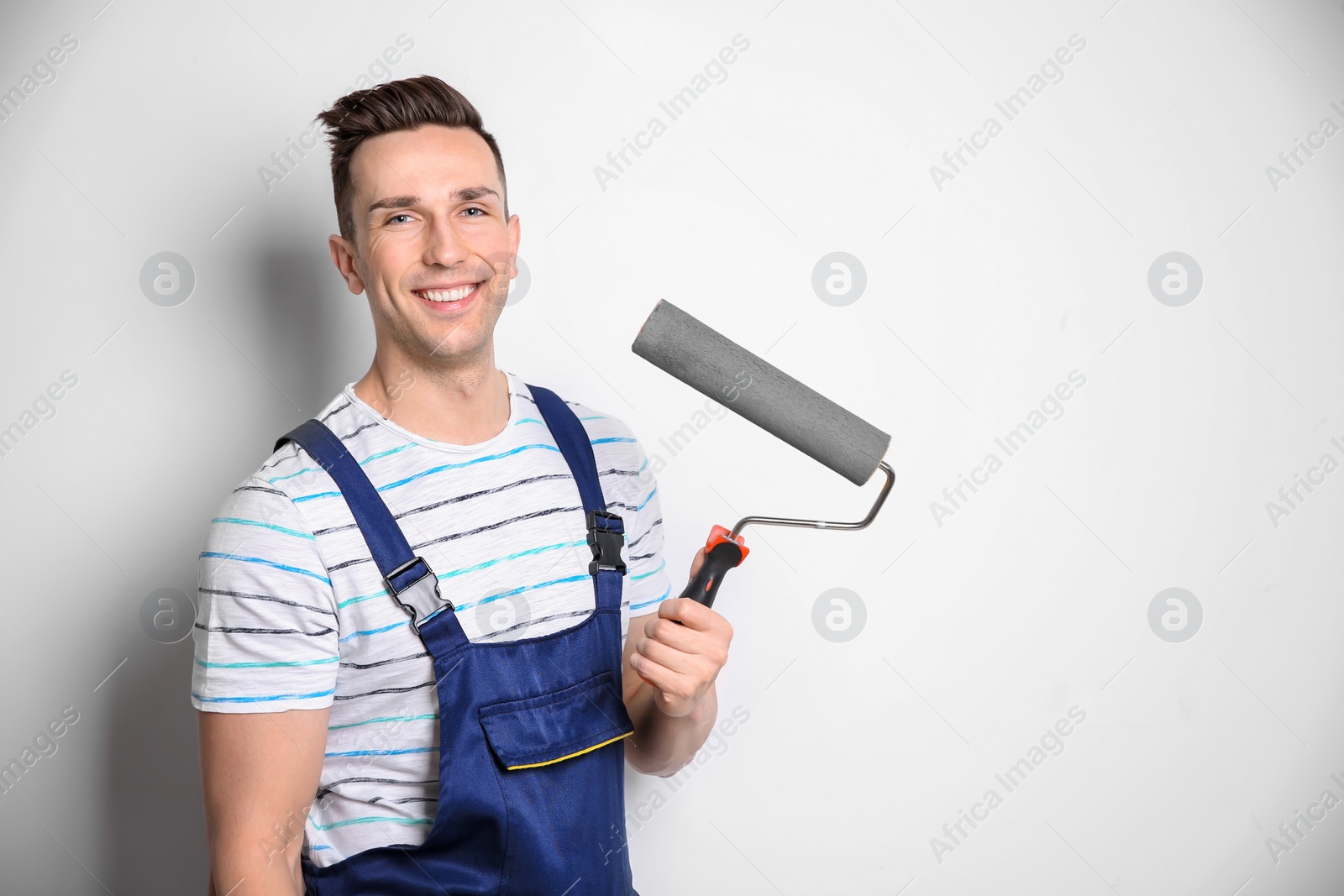 Photo of Young male decorator with paint roller on white background