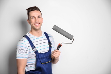 Young male decorator with paint roller on white background