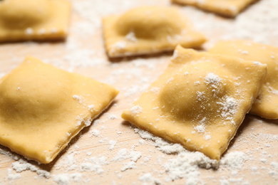 Photo of Raw ravioli on wooden board, closeup view. Italian pasta