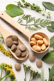 Photo of Different pills, herbs and flowers on white wooden table, above view. Dietary supplements