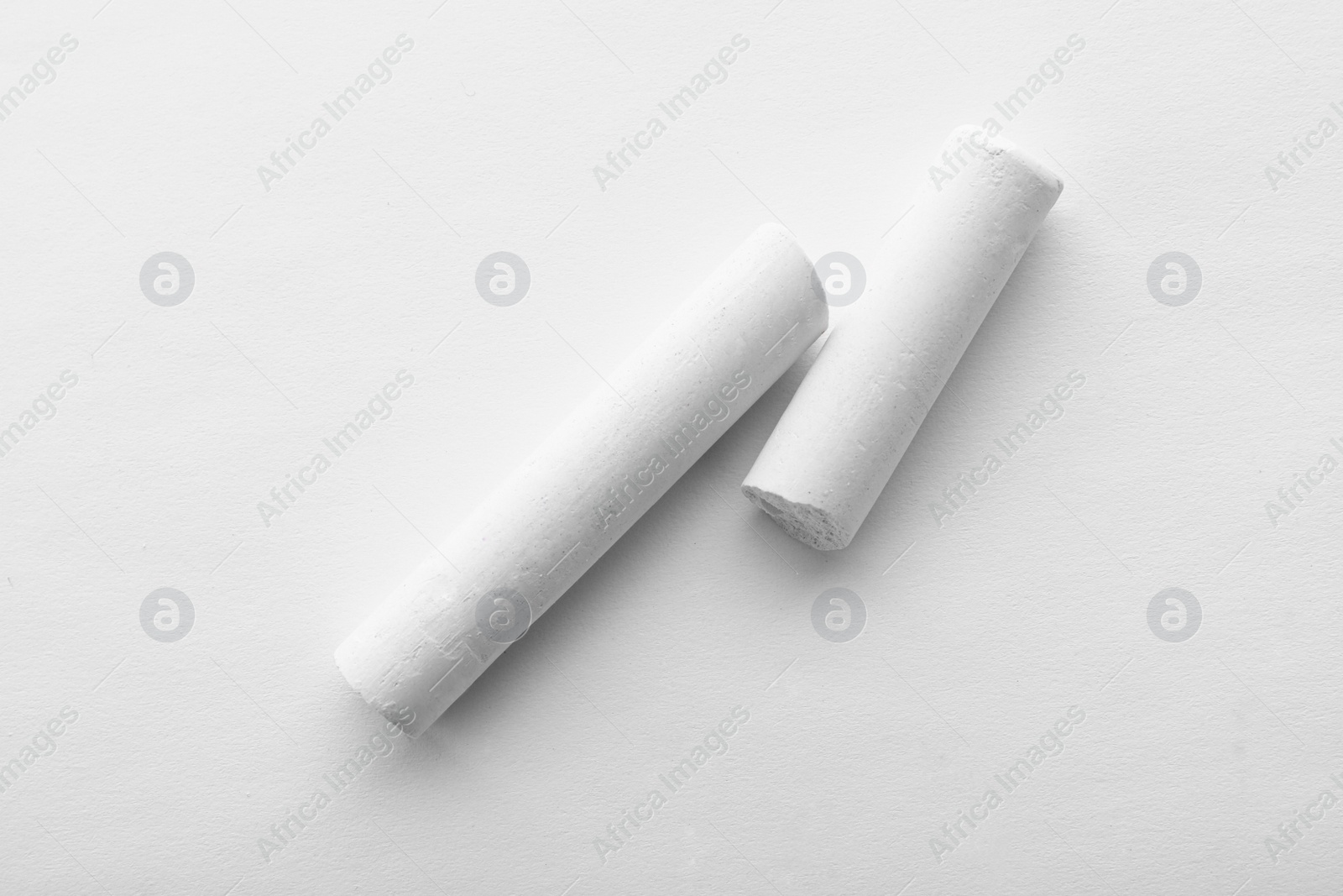 Photo of Pieces of chalk on white background, top view