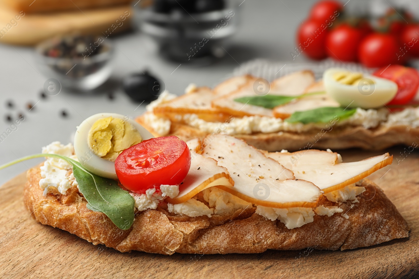 Photo of Board with delicious chicken bruschettas on table, closeup