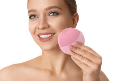 Young woman washing face with cleansing brush on white background. Cosmetic product