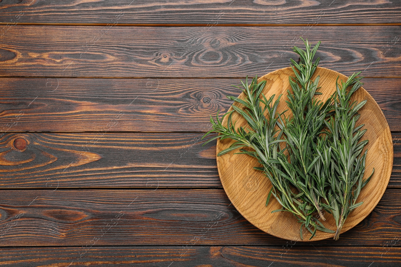 Photo of Bunch of fresh rosemary on wooden table, top view. Space for text