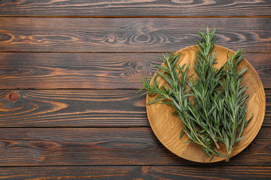 Photo of Bunch of fresh rosemary on wooden table, top view. Space for text