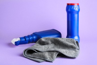 Photo of Grey microfiber cloth and detergents on light background