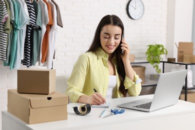 Seller talking on phone while working with laptop in office. Online store