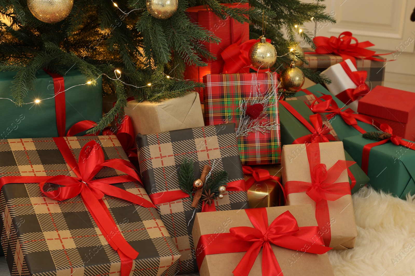 Photo of Many gift boxes under beautiful Christmas tree in room