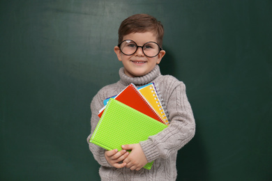 Cute little child wearing glasses near chalkboard. First time at school