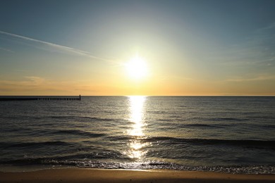 Photo of Picturesque view of sandy beach and sea at sunset