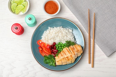 Photo of Boiled rice with vegetables and meat served on wooden table, flat lay