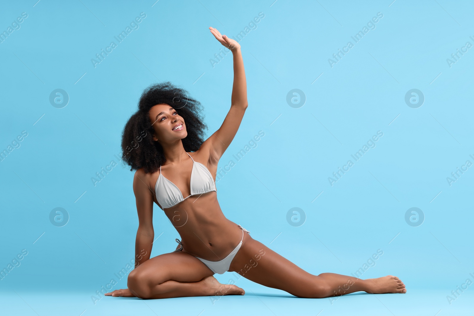 Photo of Beautiful woman in stylish bikini posing on light blue background
