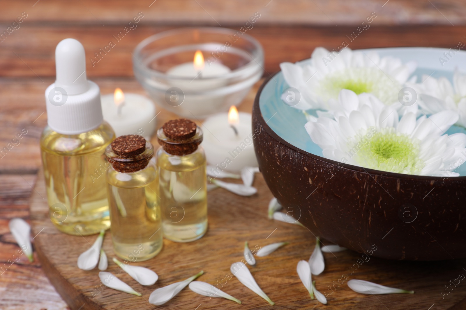 Photo of Beautiful composition with bowl of water, flowers and essential oils on table, closeup. Spa treatment