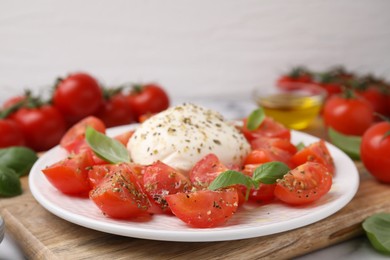 Tasty salad Caprese with mozarella, tomatoes and basil on table, closeup
