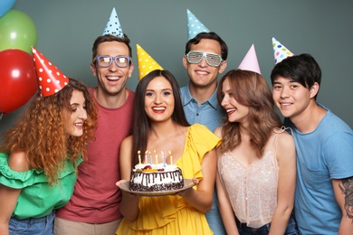 Photo of Young people celebrating birthday with tasty cake on color background