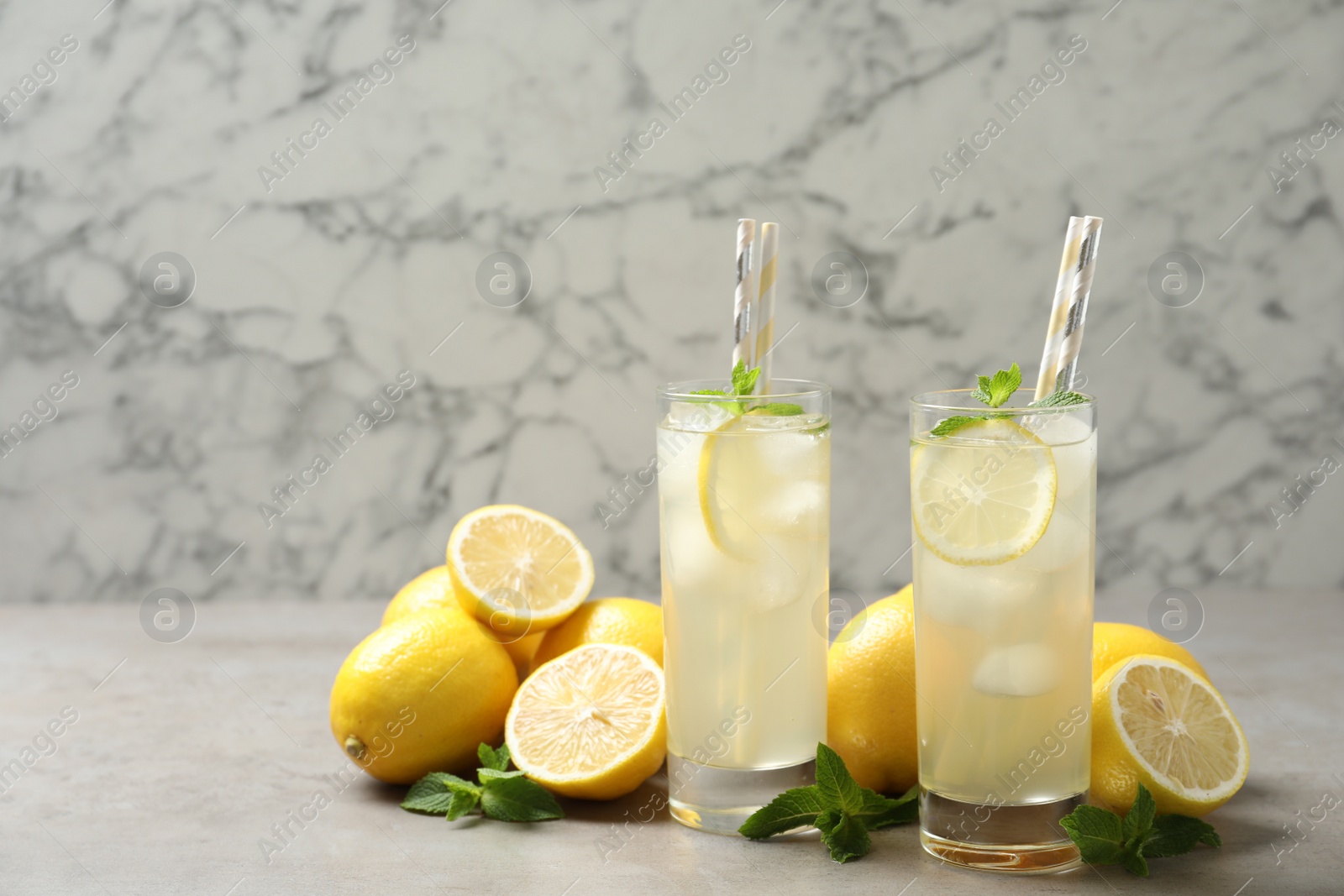 Photo of Natural lemonade with mint and fresh fruits on light grey table. Summer refreshing drink