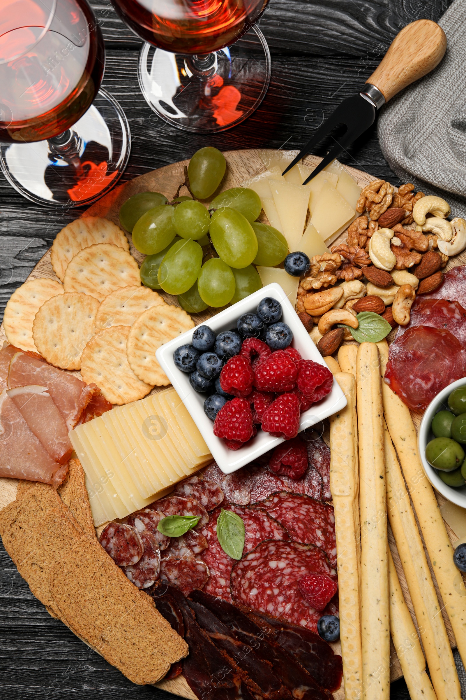 Photo of Wine and snack set with delicious Parmesan cheese on black wooden table, flat lay