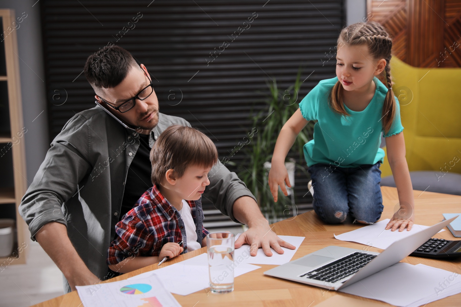 Photo of Overwhelmed man combining parenting and work at home