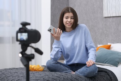 Smiling teenage blogger with smartphone streaming at home