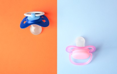 Photo of Baby pacifiers on color background, flat lay