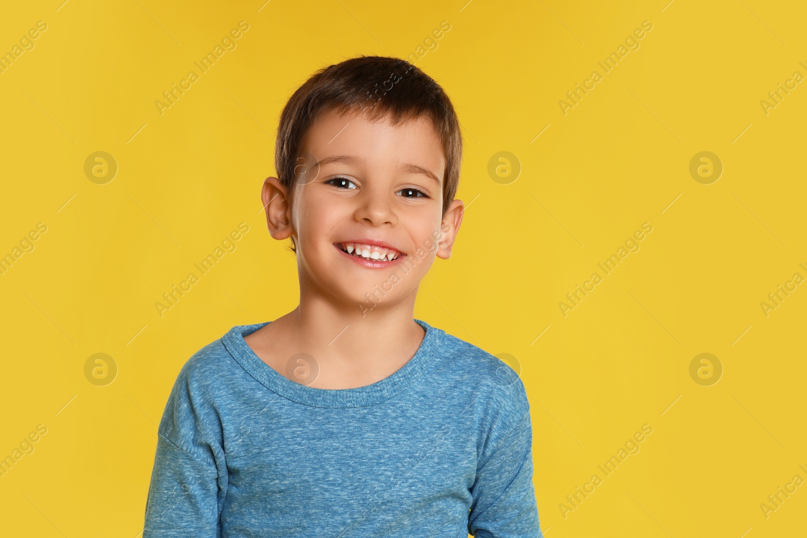 Photo of Portrait of happy little boy on yellow background