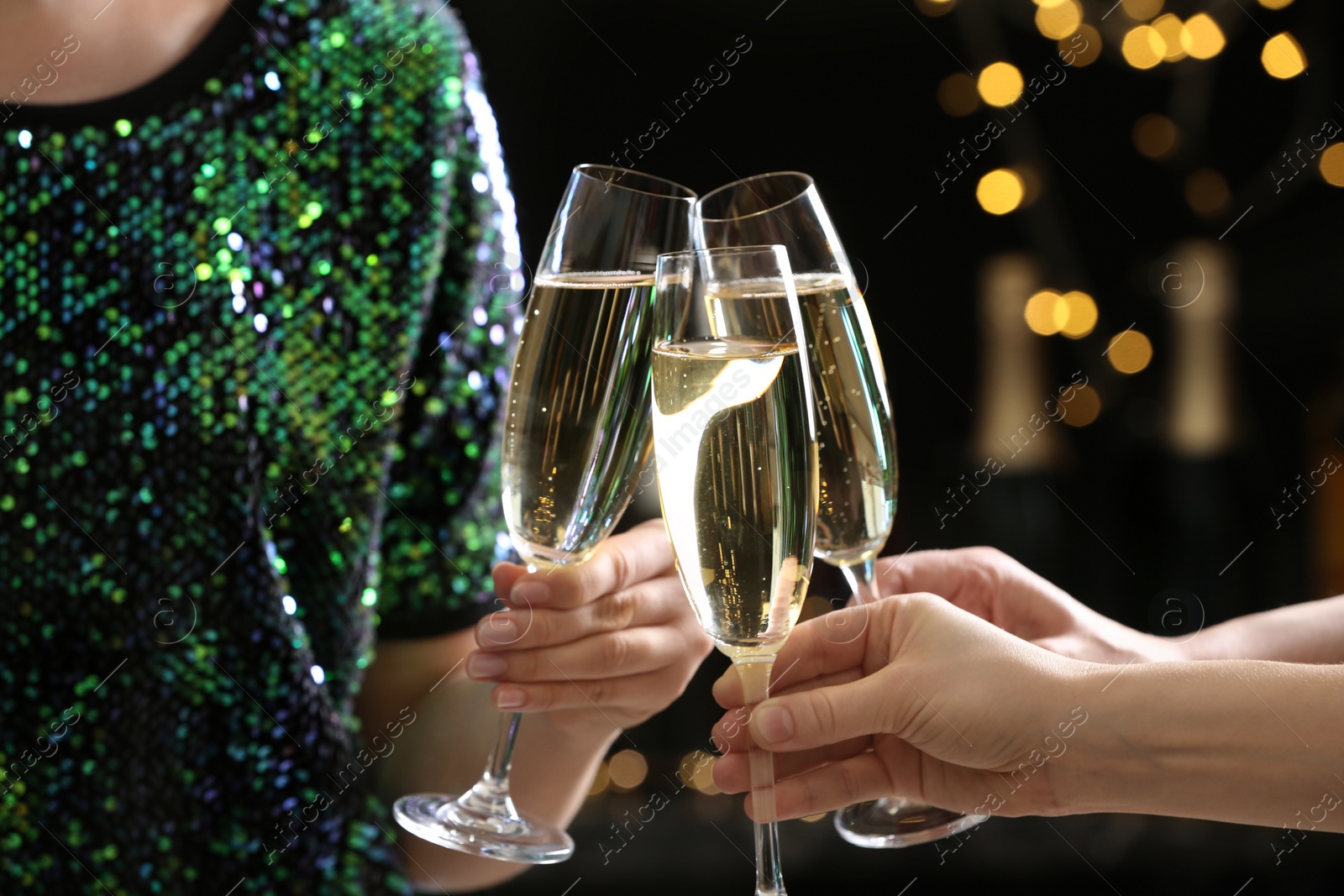 Photo of People clinking glasses of champagne on blurred background, closeup