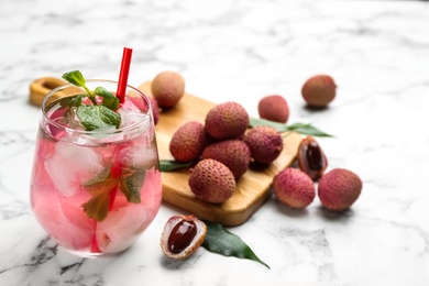 Delicious lychee cocktail and fresh fruits on white marble table. Space for text