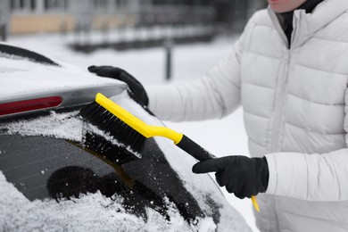 Photo of Man cleaning snow from car window outdoors, closeup