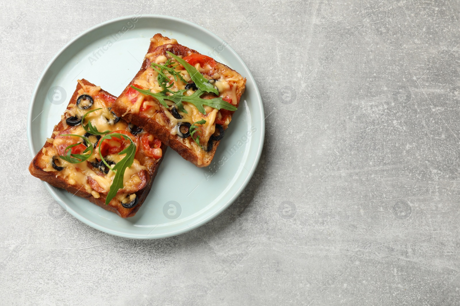 Photo of Tasty pizza toasts served on grey table, top view. Space for text