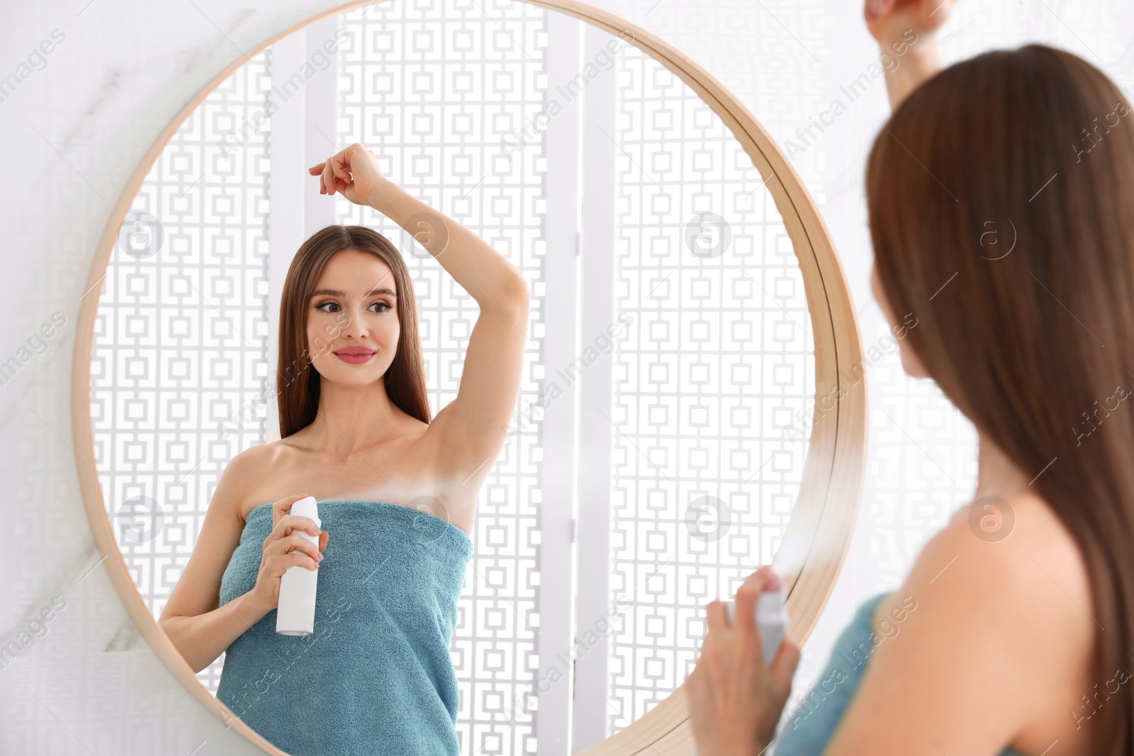 Photo of Beautiful young woman applying deodorant after shower in bathroom