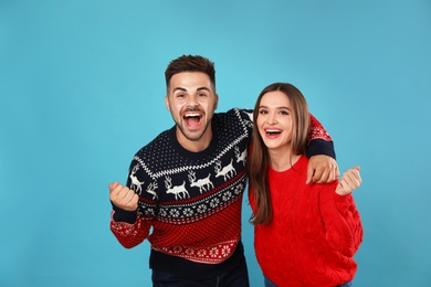 Photo of Couple wearing Christmas sweaters on blue background