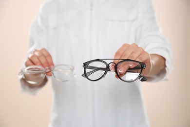 Photo of Female ophthalmologist with eyeglasses on light background, closeup