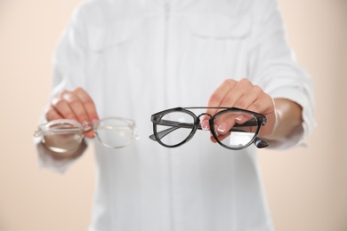 Female ophthalmologist with eyeglasses on light background, closeup