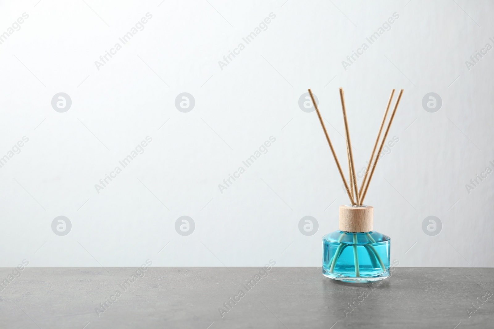 Photo of Reed air freshener on grey table against white background, space for text