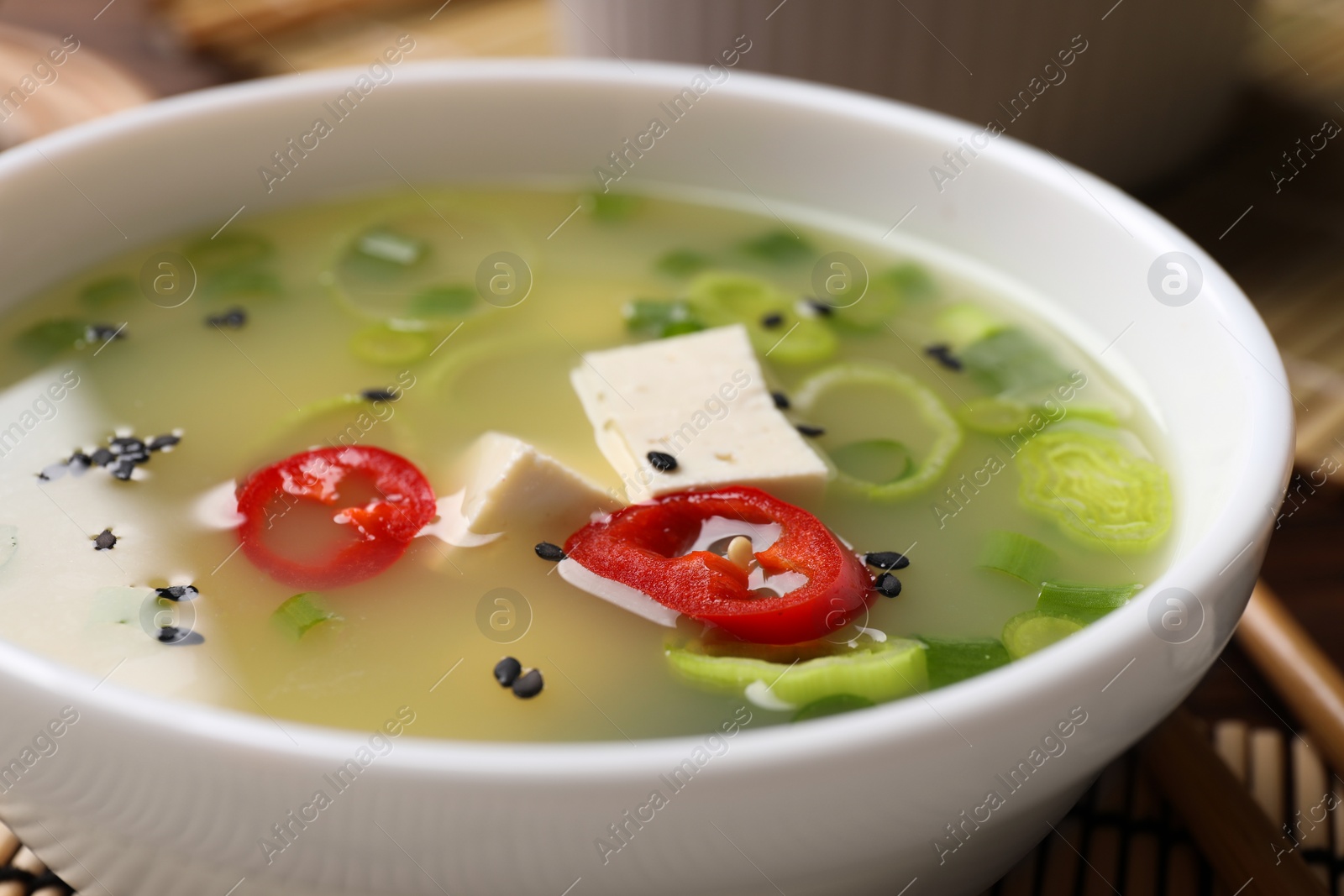 Photo of Bowl of delicious miso soup with tofu on table, closeup
