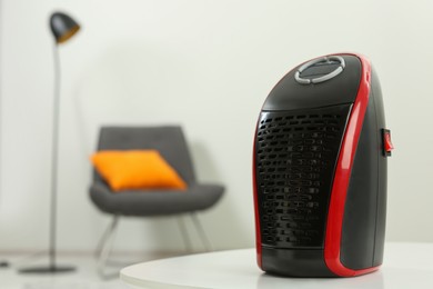 Compact electric heater on white table indoors, closeup. Space for text