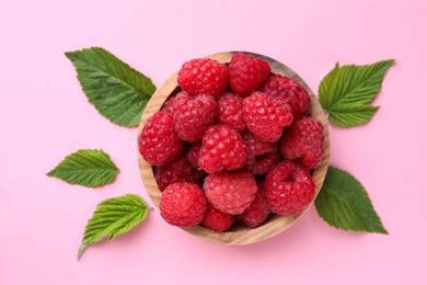 Photo of Tasty ripe raspberries and green leaves on pink background, flat lay