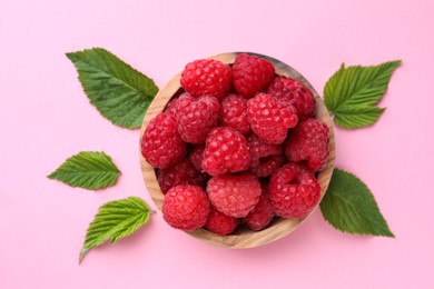 Tasty ripe raspberries and green leaves on pink background, flat lay